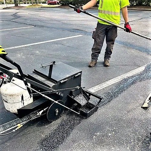 Wheeled mastic dispenser applying hot mastic to an asphalt crack